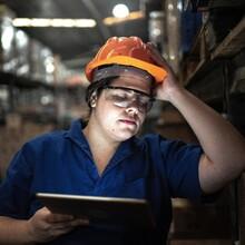 Woman at work holding a tablet displays signs of fatigue or stress