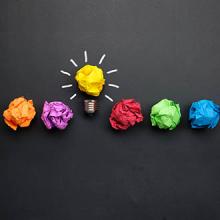Great idea concept with crumpled colorful paper and light bulb on black background