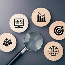 Magnifying glass and wooden icons representing data analysis, audience targeting, performance metrics, and social media goals for effective