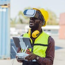 Man with VR glasses and a safety vest operates a drone
