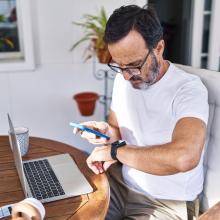 A man working from home looking at his phone and smart watch