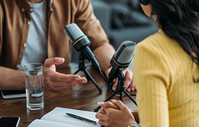 Cropped view of two radio hosts recording podcast in broadcasting studio 