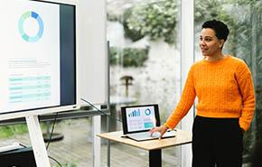 Woman showing PowerPoint chart giving training using laptop and monitor 