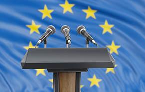 Podium lectern with microphones and European Union flag in background 