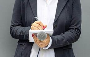 Public relations - PR officer at media event holding microphone taking notes, preparing press release